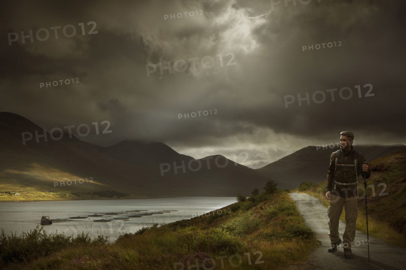 Caucasian hiker holding walking stick on path near river