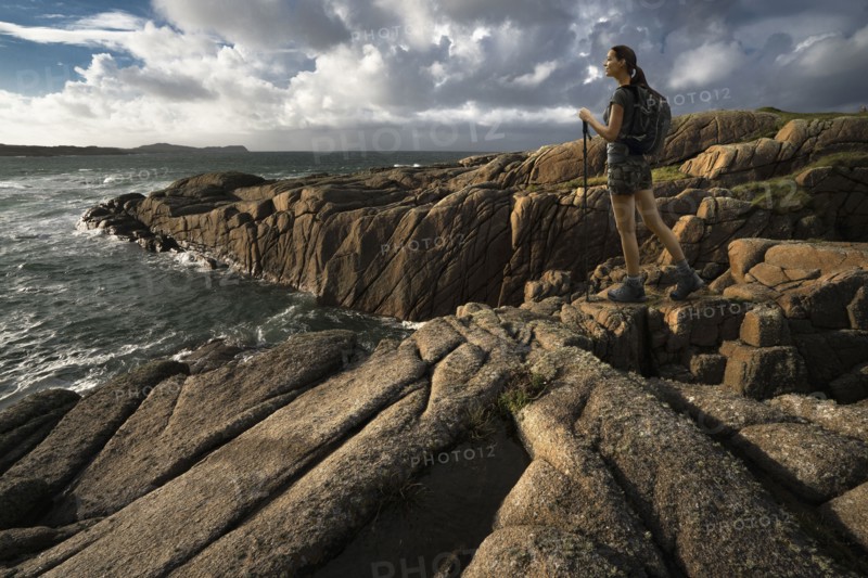 Caucasian woman hiking on rocks near ocean