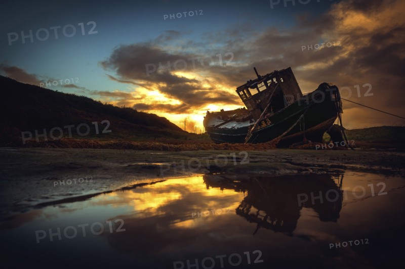 Shipwreck on beach at sunset