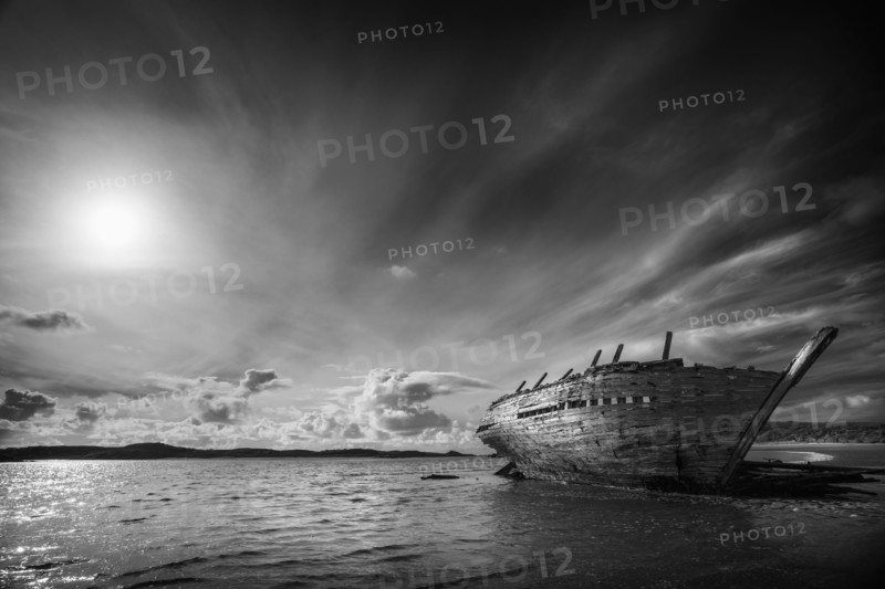 Shipwreck on beach under clouds