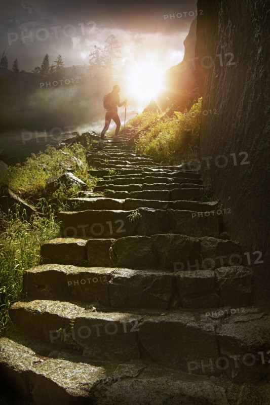 Distant hiker on stone staircase at sunset
