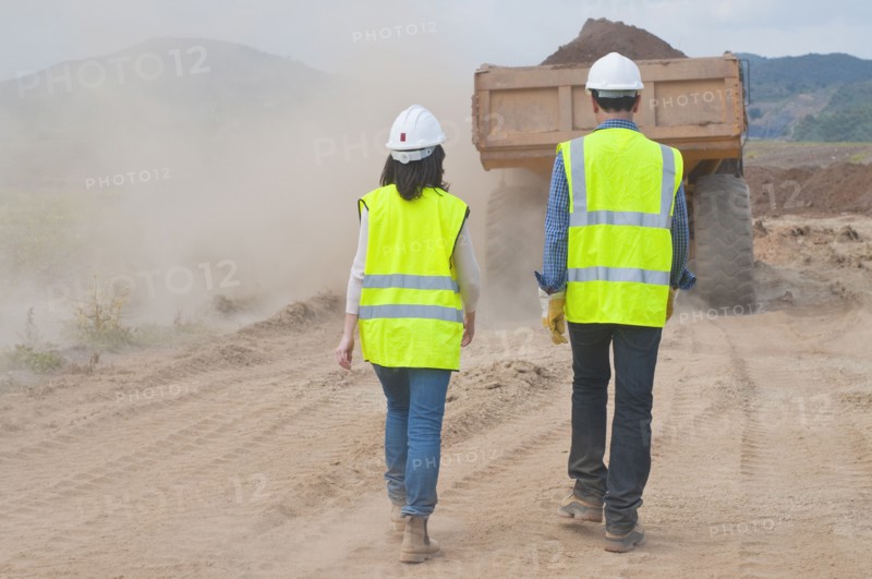 Construction workers walking behind dump truck
