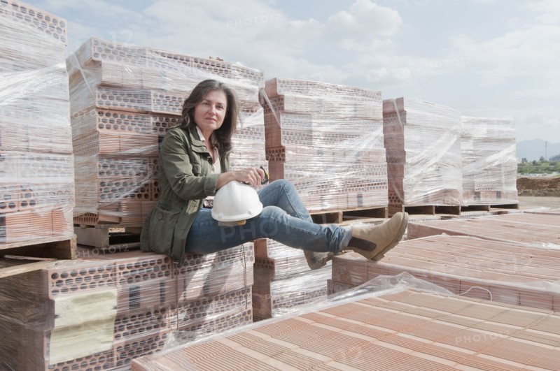 Caucasian construction worker sitting on stack of bricks