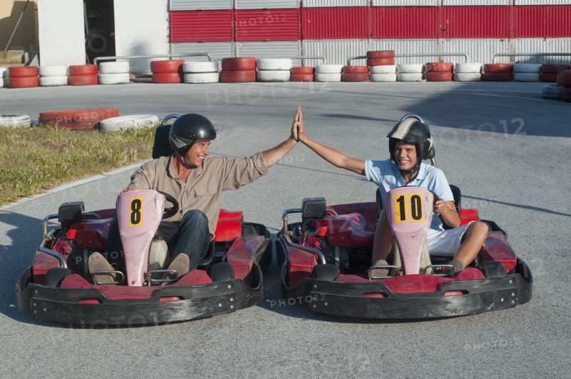 Hispanic grandfather and grandson on go-cart track