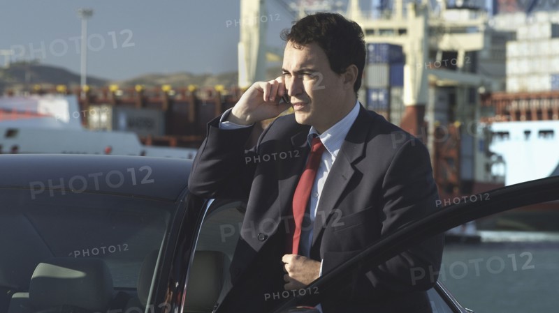 Hispanic businessman talking on cell phone on dock