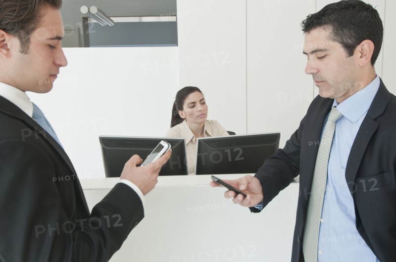 Hispanic businessmen holding cell phones in office