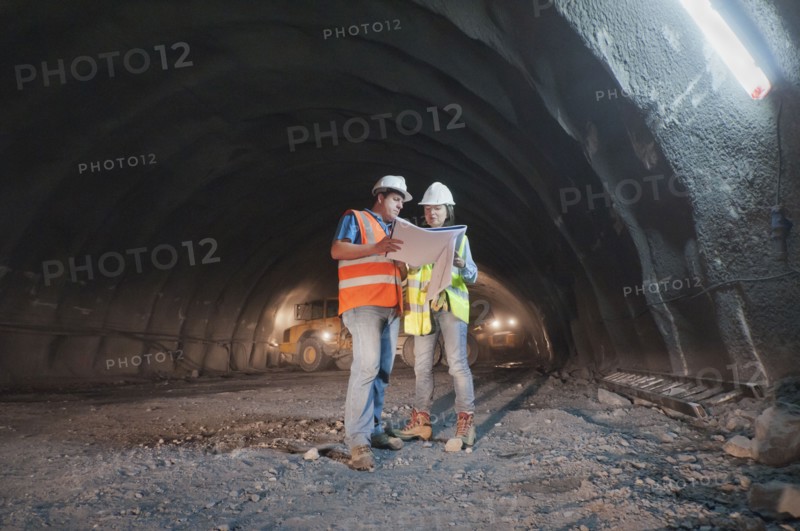 Construction workers looking at blueprint in tunnel