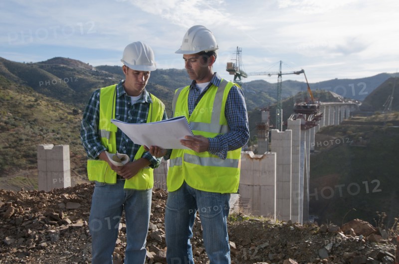Construction workers looking at blueprint at construction site
