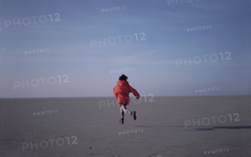 Woman running on sand flats rear view
