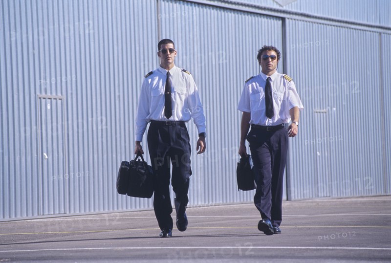 Two pilots walking in front of hangars