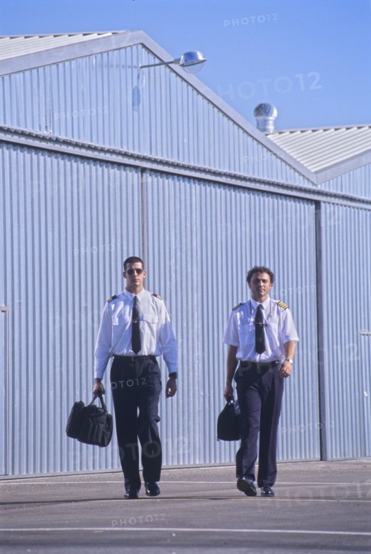 Two pilots walking in front of hangars