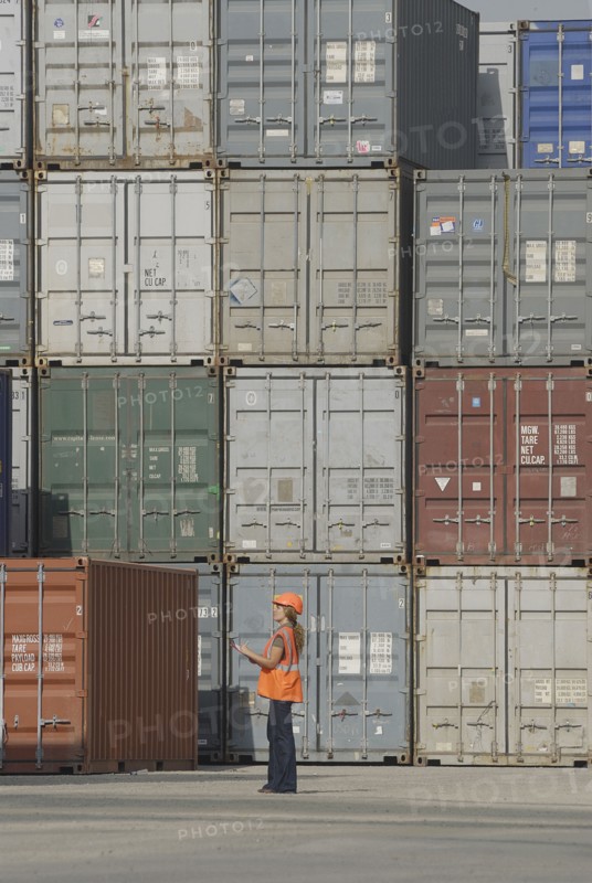 Female worker with clipboard in cargo container terminal low angle