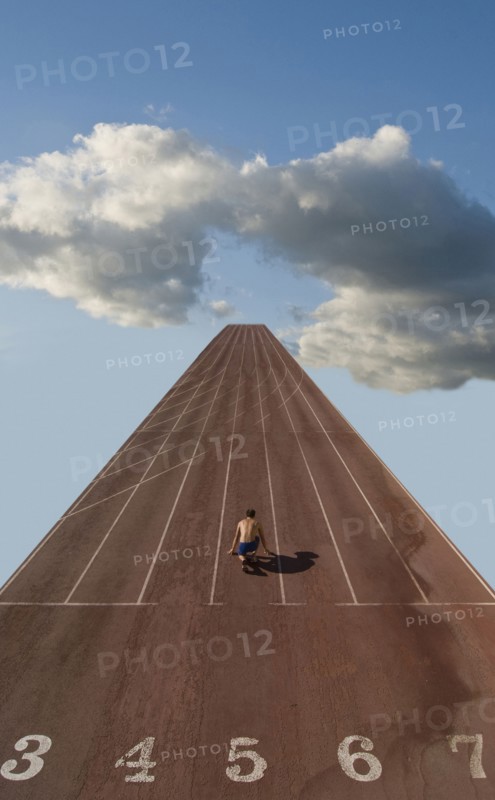 Lone sprinter at starting position on track in clouds (Digital Composite)