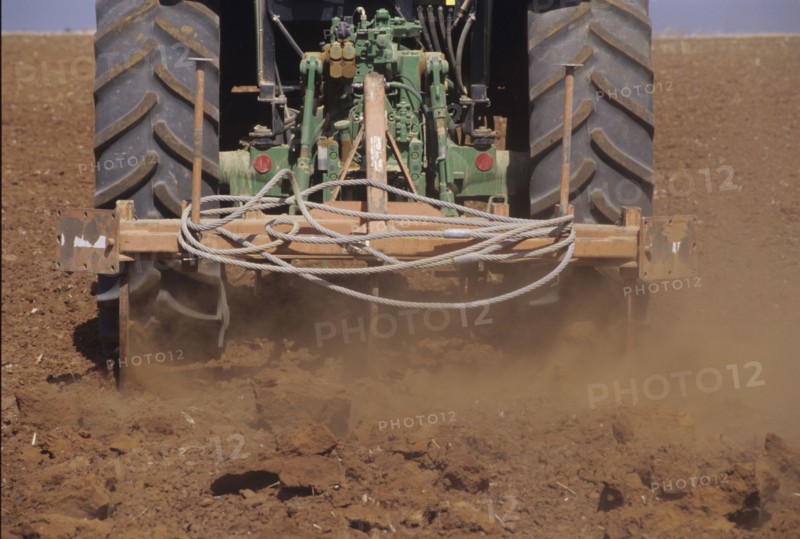 Low Section of a Tractor Ploughing the Soil in a Field