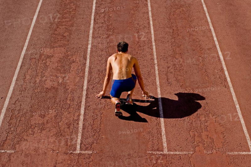 Runner on starting position of running track rear view