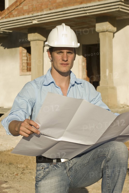 Young architect with plan on construction site