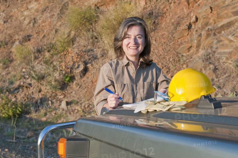 female engineer using car hood as desk