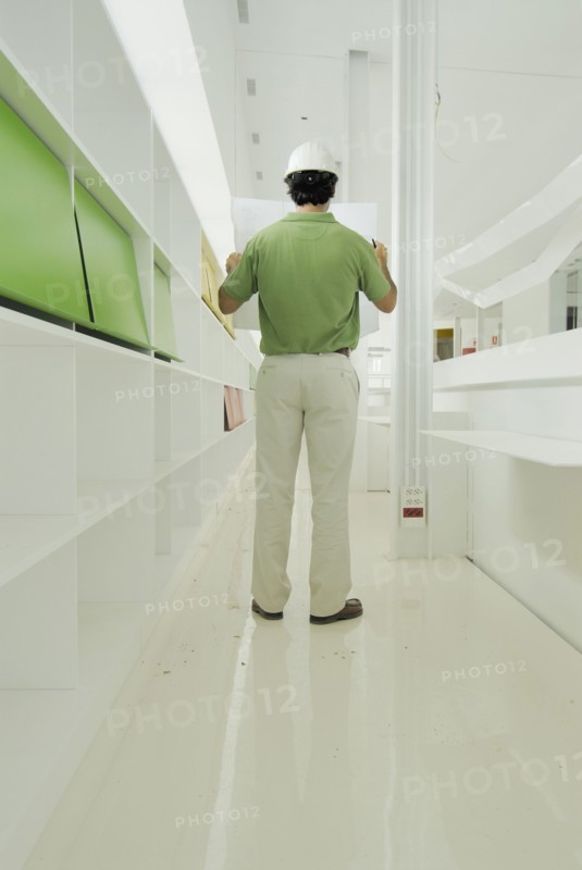 Male architect looking at plan in recently finished office building