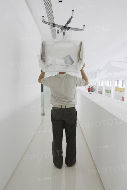 Man carrying chair thorugh office rear view