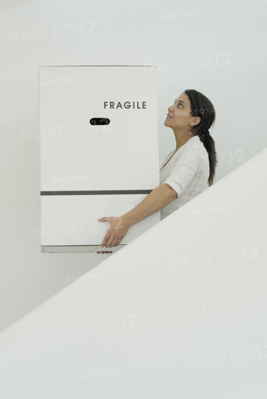 Woman carrying boxes downstairs side view