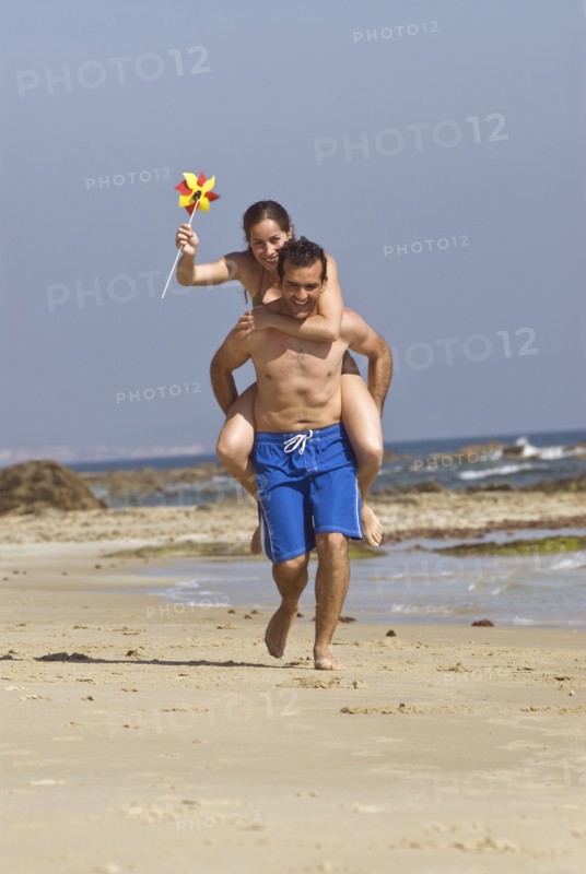 Man carrying woman on shoulders on beach