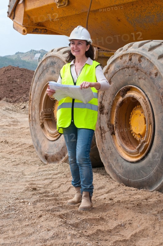 female engineer with plan next to dump truck