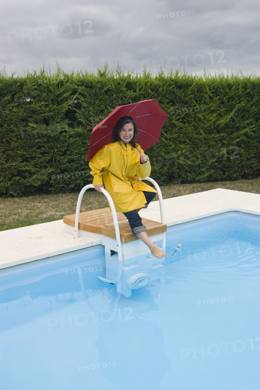 woman in rainwear tipping toe into swimming pool