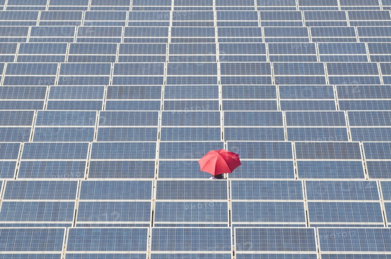 woman holding red umbrella in solar plant