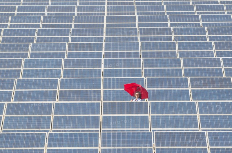 woman holding red umbrella in solar power plant