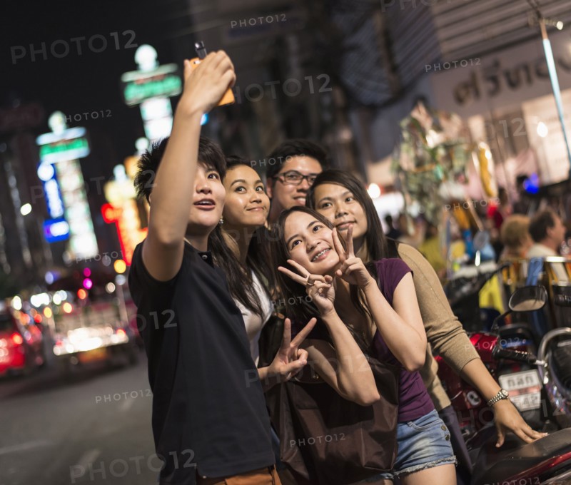 Friends taking pictures on city street at night