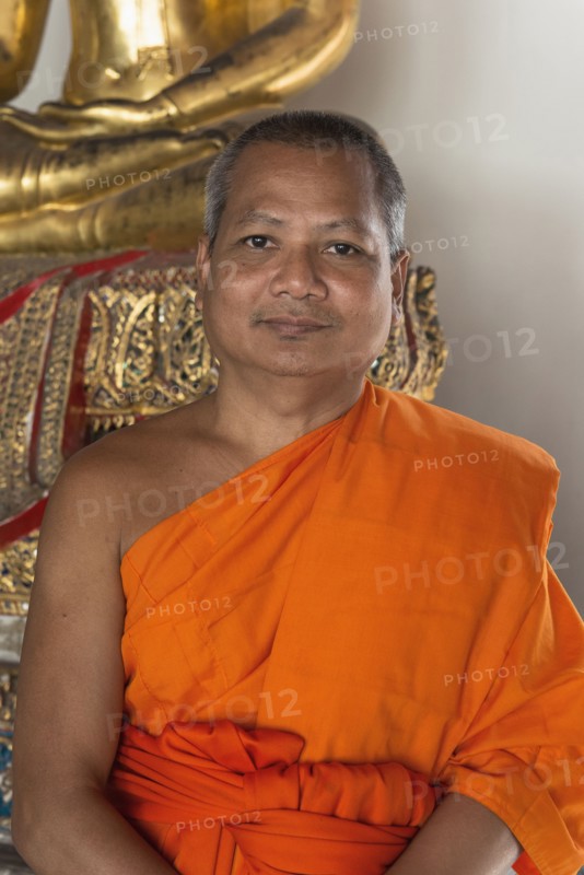 Thai Buddhist monk smiling near statue