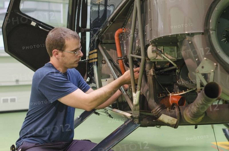 Hispanic mechanic working on helicopter in hangar