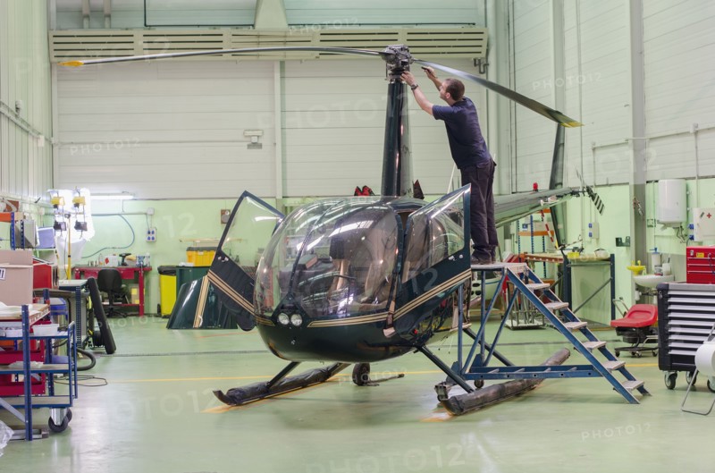 Hispanic mechanic working on helicopter in hangar