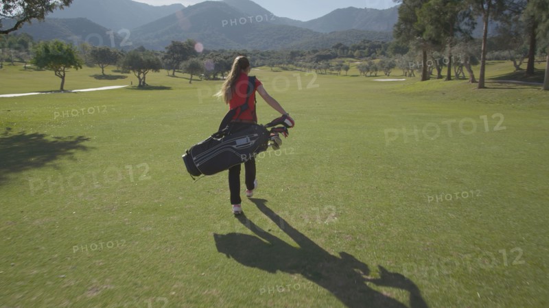 Caucasian woman carrying golf bag on course