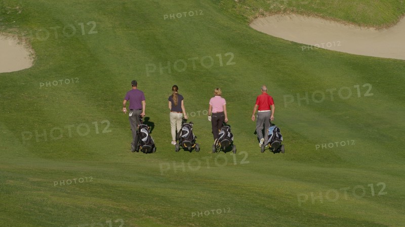 Caucasian friends pulling golf bags on course