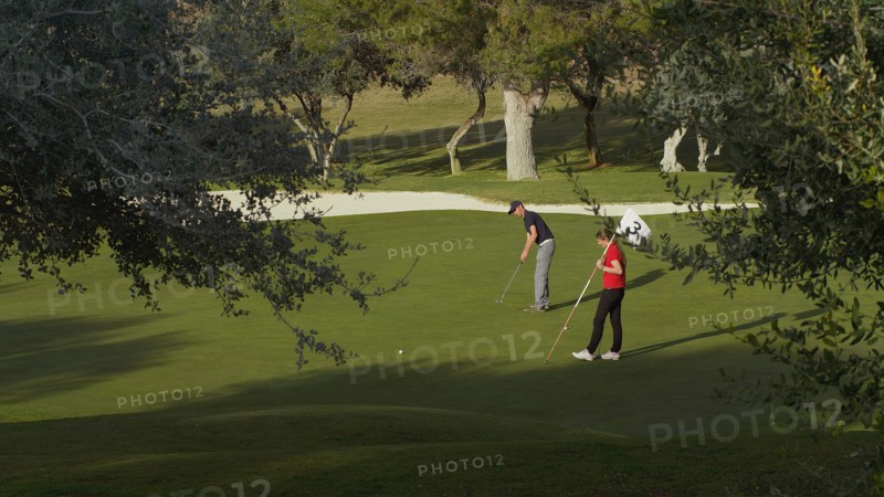 Caucasian couple putting on golf course