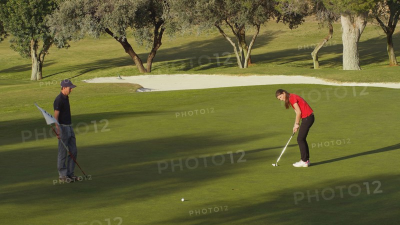 Caucasian couple putting on golf course