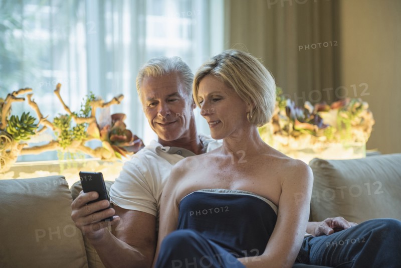 Caucasian couple using cell phone in hotel lobby