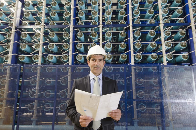 Hispanic businessman smiling in power plant