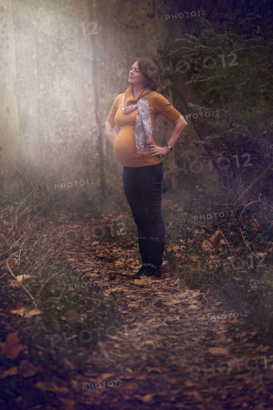 Pregnant Caucasian woman standing in forest