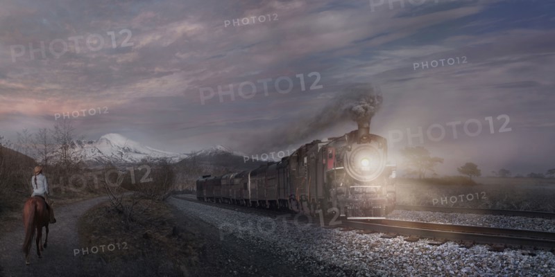 Woman on horse watching train in remote landscape
