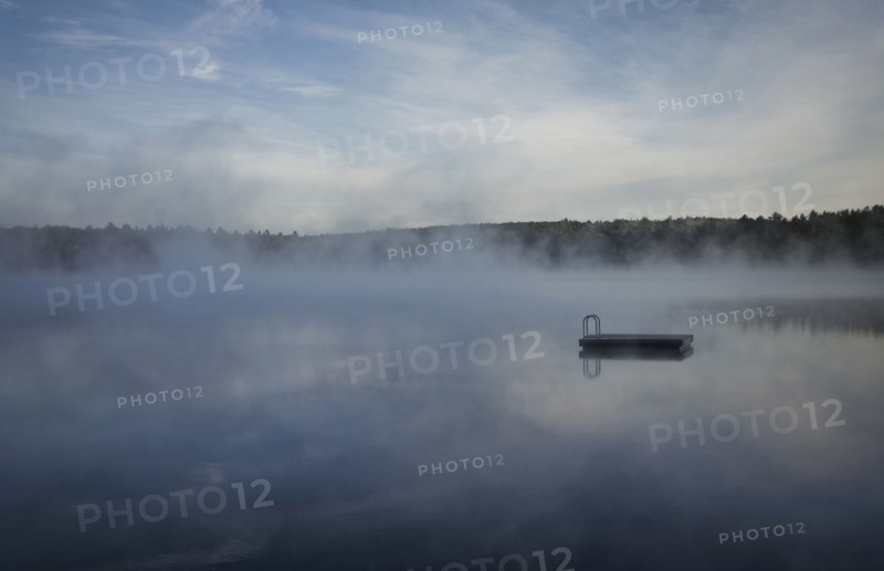 Mist clouds over still lake in remote landscape