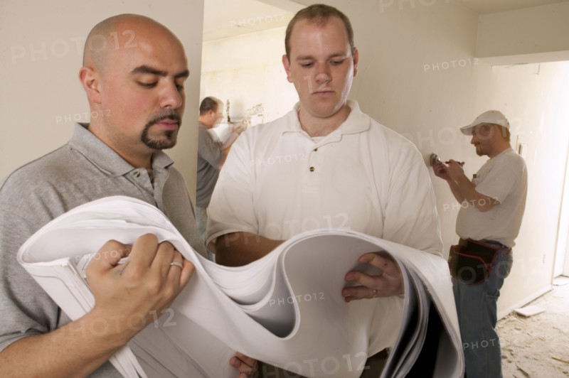 Contractors examining blueprints in house