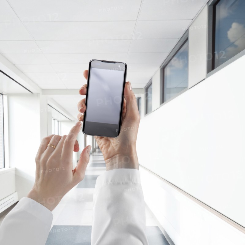 Businesswoman using cell phone in white corridor