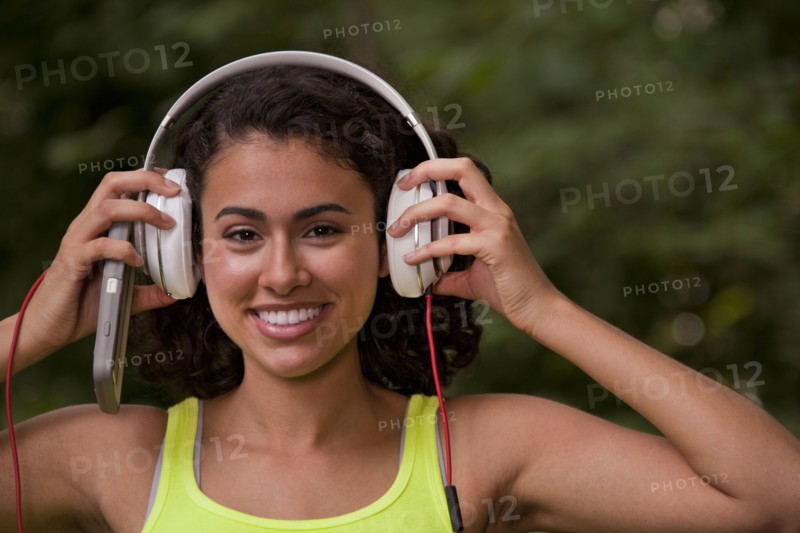 Hispanic woman listening to headphone and cell phone in forest