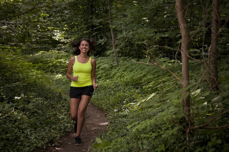 Hispanic woman running on path in forest