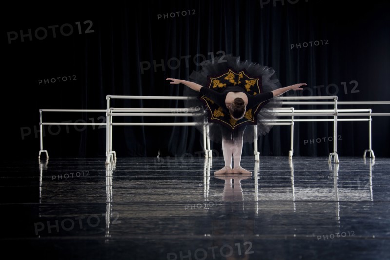 Caucasian ballerina bowing on dark stage