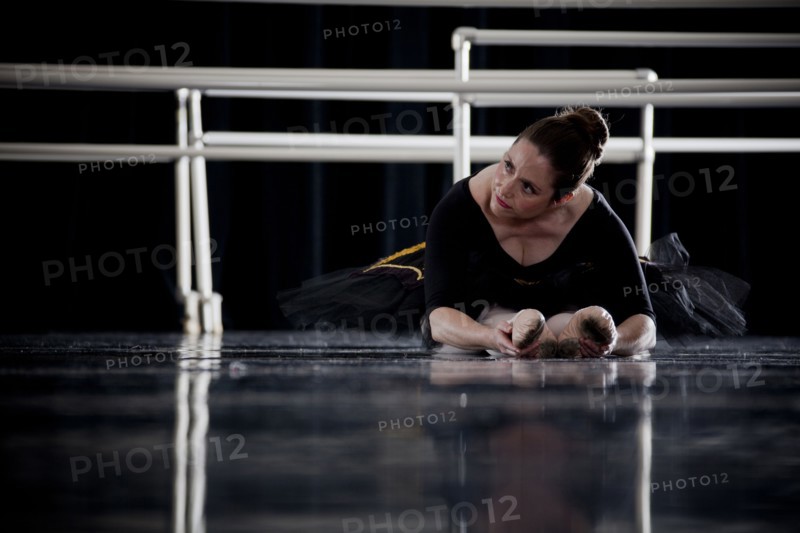 Caucasian ballerina stretching legs on dark stage