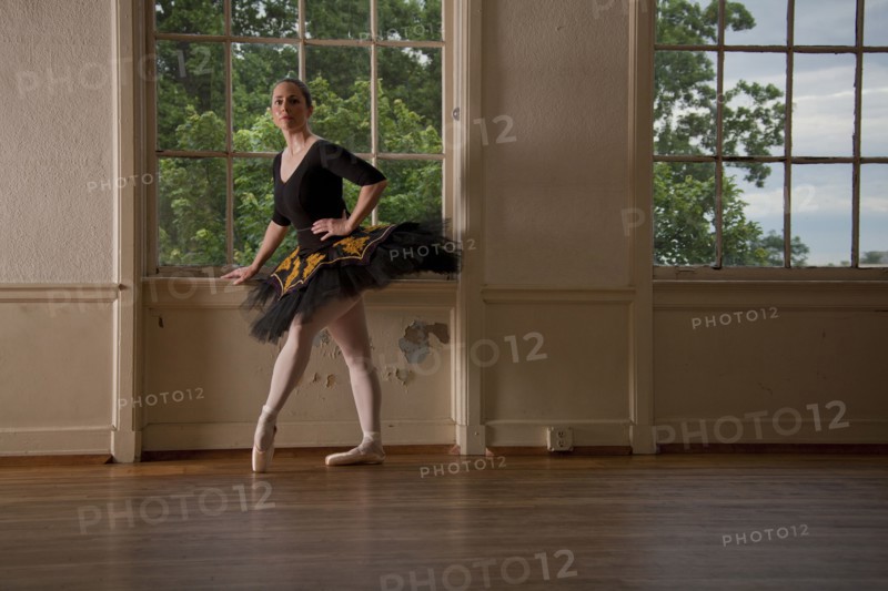 Caucasian ballerina posing at window in studio