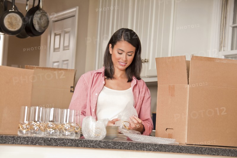 Smiling Hispanic woman packing dishes in kitchen